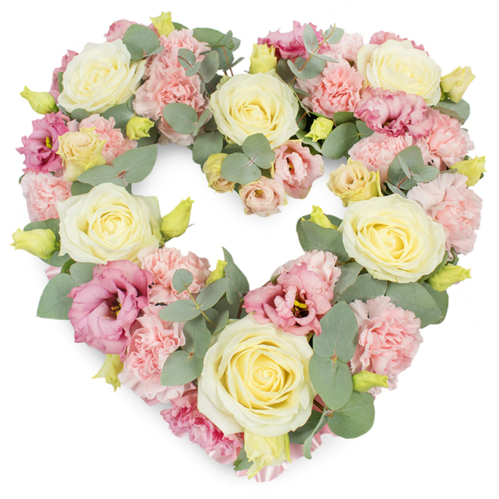 A tender heart-shaped wreath designed as a funeral or memorial tribute is shown against a pure white background, its pastel flowers and cool greenery reflecting the gentle side of New Southgate's community. Florist New Southgate might create such a piece for a farewell at a local chapel or service near Bounds Green, where family and friends gather to share memories. The heart itself is densely composed, with no empty spaces, forming a clear and perfectly balanced outline. Cream and soft yellow roses take pride of place throughout the arrangement; their petals spiral tightly from the centre and gradually unfurl, giving the impression of carefully held emotions and enduring love. Nestled between the roses, dozens of pastel pink carnations open in ruffled layers, their frill-edged petals creating texture akin to soft fabric or lace, lending the design a comforting, almost embracing feel. Deeper magenta and mauve-pink lisianthus blooms appear at intervals, their more open, cup-like flowers and slightly darker centres adding dimension and a gentle sense of depth, like recollections that surface and recede in the mind. Cool, silvery-green eucalyptus threads through the heart, its rounded leaves peeking between petals, providing contrast and a subtle suggestion of soothing fragrance. Scattered yellow-green buds, still partly closed, bring small accents of fresh life, reminding the viewer of continuity amid sorrow. The white background keeps attention firmly on the heart, allowing each pastel tone and carefully placed stem to stand out. This floral tribute conveys love, sympathy, and remembrance in a soft, understated way, suitable for a New Southgate funeral, cremation ceremony, or condolence delivery to a grieving home, where it can act as a gentle visual expression of support.