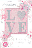 This anniversary card is a gentle tribute to enduring romance, its design unfolding in soft pastel pinks, silvery greys, and creamy whites. The eye is drawn first to the word "LOVE," set at the centre in raised, soft glitter that catches the light like tiny crystals. The letters feel substantial yet delicate, with the "O" transformed into a shimmering heart filled with textured silver, turning the word itself into a miniature artwork. Around this focal point, delicate blossoms in blush and mauve bloom across the card, their petals painted with a watercolour softness that suggests fresh, just-opened flowers in a New Southgate florist's display. Fine, flowing lines trace stems and leaves, while tiny details-curling tendrils, swirling flourishes, and near-hidden butterfly shapes-add a sense of motion and whimsy. The floral motifs evoke the quiet charm of an English spring garden, not unlike the peaceful greenery found around local parks and tree-lined streets. The phrases "On Our Anniversary" and "I love you today and always" are written in a graceful, flowing script, understated but heartfelt, as if meant to be read softly between two people. The composition feels balanced and airy, with plenty of space for the flowers and lettering to breathe, mirroring the calm and familiarity of a long-standing relationship. This card captures the essence of placing a hand-tied bouquet on a dining table in New Southgate after a special delivery: a simple yet profound reminder of shared journeys, whispered promises, and love that has grown deeper with every passing year.